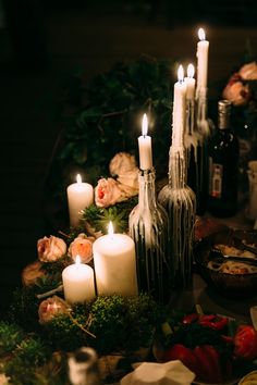 candles are lit in front of bottles and flowers on a table with other items around it