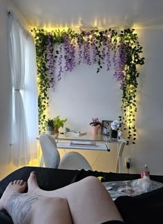 a woman laying on top of a bed next to a desk covered in purple flowers