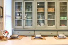 a dining room table with plates and bowls on it, next to a china cabinet