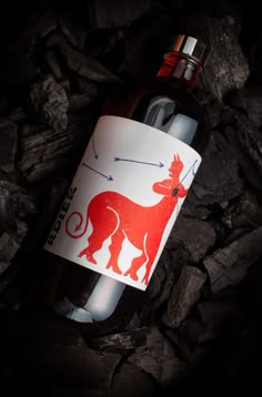 a bottle of red wine sitting on top of rocks with an arrow pointing to the right