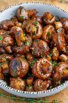 a white bowl filled with mushrooms and garnished with parsley on the side