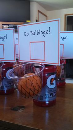 three cups with basketballs in them sitting on top of a wooden table next to a sign that says go bulldogs