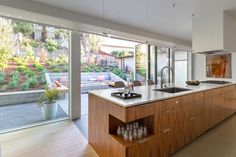 a kitchen with an island, sink and stove top oven next to a sliding glass door