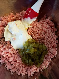 the food is mixed together in a bowl with a red spatula and white sauce