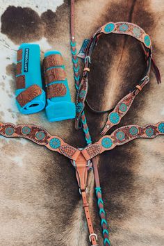 a horse's bridle and reins laying on top of a cowhide rug