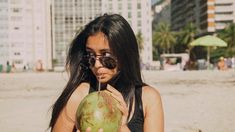 a woman holding a coconut on the beach