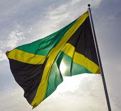 a flag flying in the wind on a cloudy day with sun shining through clouds behind it