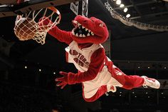 a person in a red and white dinosaur costume dunks a basketball into the hoop