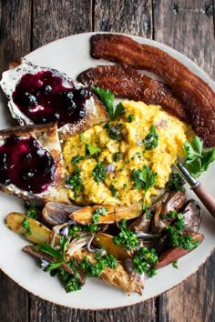 a white plate topped with eggs, mushrooms and other foods on top of a wooden table