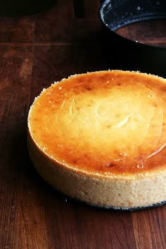 a cheesecake sitting on top of a wooden table next to a frying pan