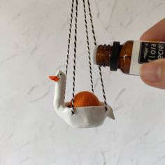 a person is holding a bottle with an orange in the shape of a bird on it