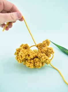 someone is crocheting something with yarn on the end and holding it in their hand