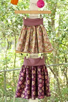 a dress made out of clothes hanging on a rack in front of some trees and bushes