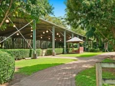 an outdoor pavilion with trees and grass in the foreground, surrounded by greenery