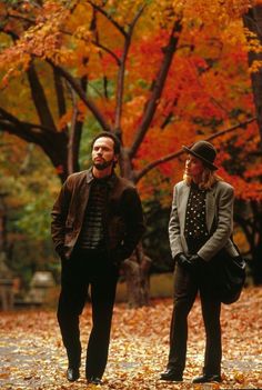 two people standing in the middle of leaves