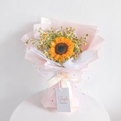 a bouquet of sunflowers and baby's breath tied to a white table