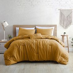 a bedroom with white walls and wooden flooring has a large yellow comforter on the bed