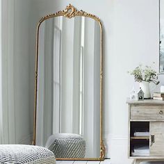 a large gold framed mirror sitting on top of a dresser