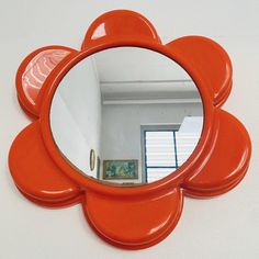 an orange flower shaped mirror hanging on the wall