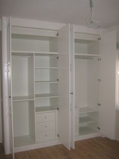 an empty room with white closets and drawers in the corner, one is open