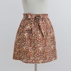 a mannequin wearing a skirt with an orange and red pattern on the front