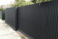 a black fence is next to a sidewalk