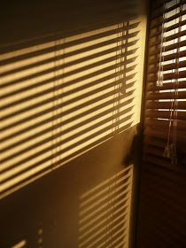 the shadow of blinds on a window is cast onto the wall