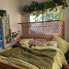 a bed sitting in a bedroom next to a window covered in green blankets and pillows