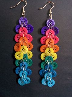 multicolored buttons hang from silver earwires on a black surface with metal hooks