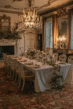 an elegant dining room with chandelier and table set for four, surrounded by floral arrangements