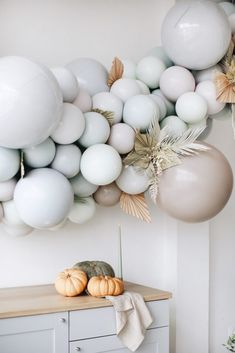 some balloons are hanging from the ceiling in front of a white wall and wooden table