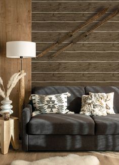 a living room with a couch, lamp and wooden wall paneling in the background