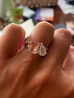 a woman's hand holding an engagement ring with two diamonds on top of it