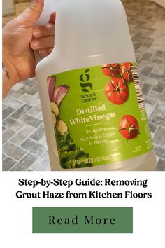 Bottle of distilled white vinegar held by a hand, used in a guide for removing grout haze from kitchen floors. How To Remove Grout, Install Backsplash, Marble Backsplash Kitchen, Clean Kitchen Floor, Old Towels, Water Solutions, Vinegar And Water, Distilled White Vinegar, Easy Jobs