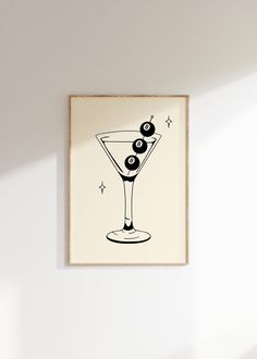 a black and white drawing of a martini glass with olives on the rim in front of a white wall