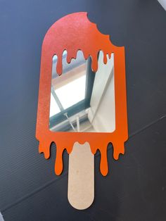 an orange mirror sitting on top of a black table