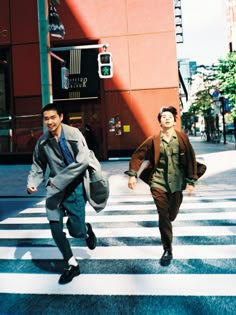 two men walking across a cross walk in the city