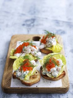 a wooden tray topped with sandwiches covered in lettuce and tomato sauce on top of bread