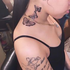 a woman with butterfly tattoos on her neck and shoulder is looking down at the camera