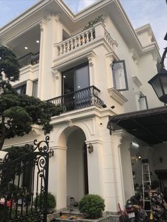 a large white house with black iron railings and balconies on the second floor