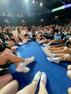 the cheerleaders are sitting in a circle on the blue carpet and looking at the crowd