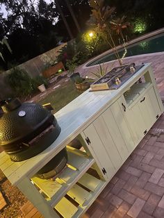 a bbq grill sitting on top of a wooden table next to a swimming pool