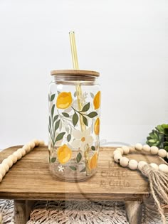 a mason jar with yellow flowers and leaves painted on the lid sitting on a wooden bench