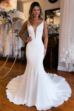 a woman wearing a white wedding dress standing in front of a mirror with her hands on her hips