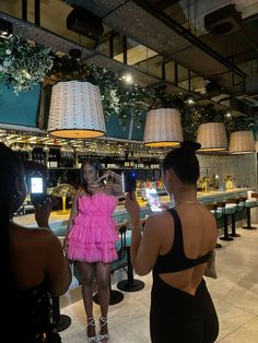 two women taking pictures in front of a bar