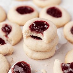 several cookies with jam on them and one has a bite taken out of the middle