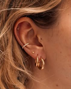 a close up of a person's ear with two gold hoops on it