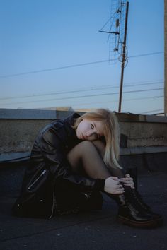 a woman is sitting on the ground with her head in her hands and looking at the camera