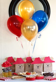 a table topped with lots of balloons and cookies