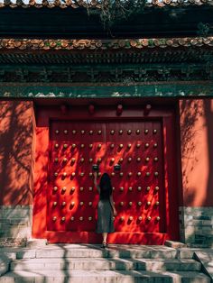 a woman standing in front of a red door